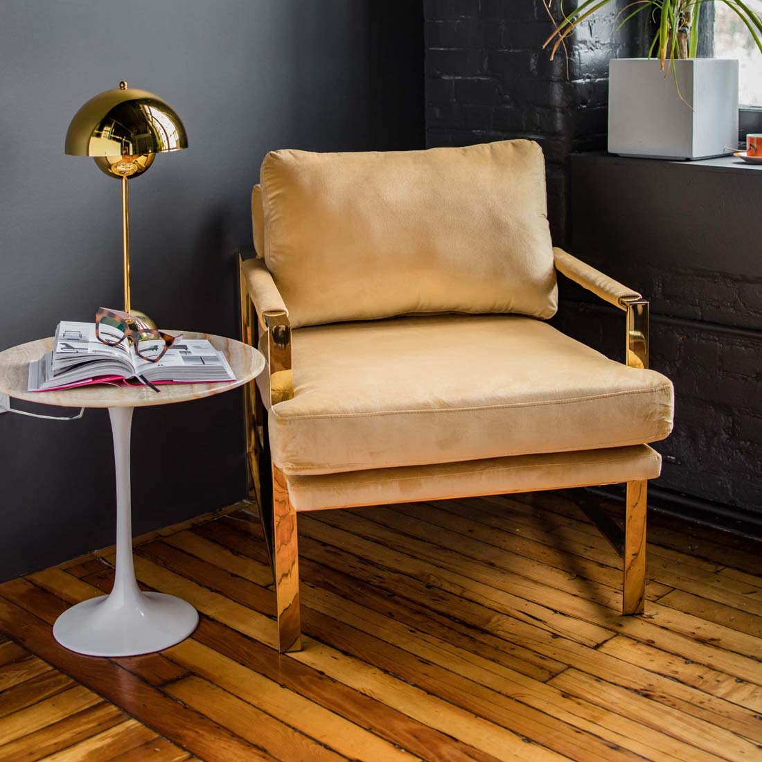 Tan and gold chair sitting on a hardwood floor, with a marble Tulip table beside it.